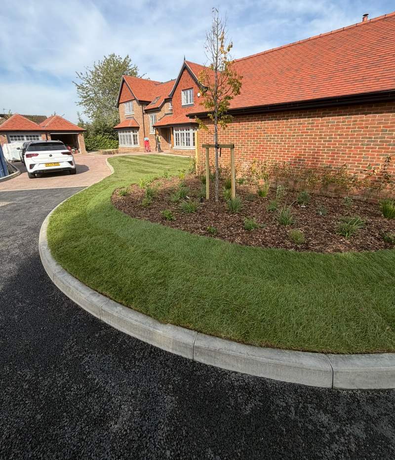 Curved turf verge, mulched bed and staked tree at a new-build housing development