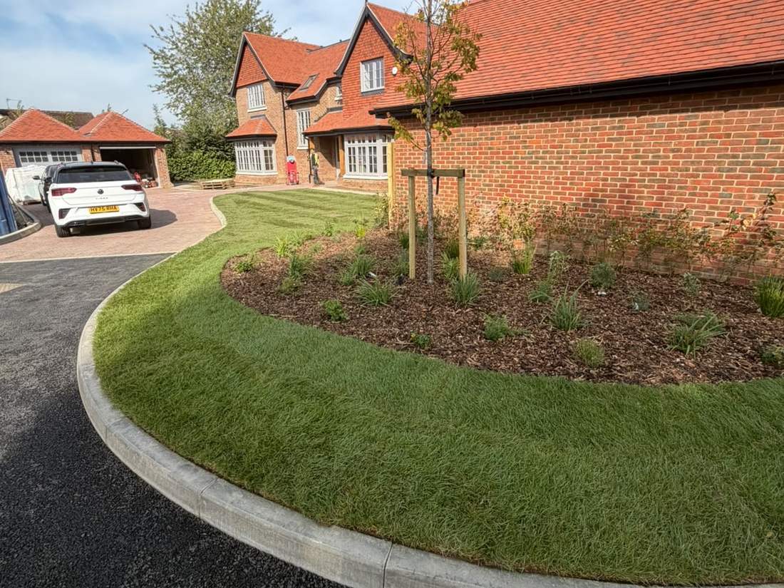Newly laid turf verge and mulched planting bed with a staked tree outside new-build homes, soft landscaping by EdenGreen Gardens